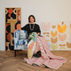 Michal Silver, Creative Director of Christopher Farr Cloth, presenting the Mikado quilt showing both front and back patchwork made from fabric offcuts, displayed in front of Véronique’s original artwork.